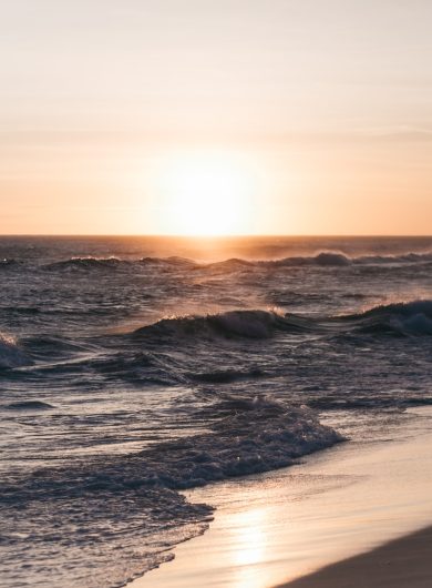 ocean waves crashing on shore during sunset